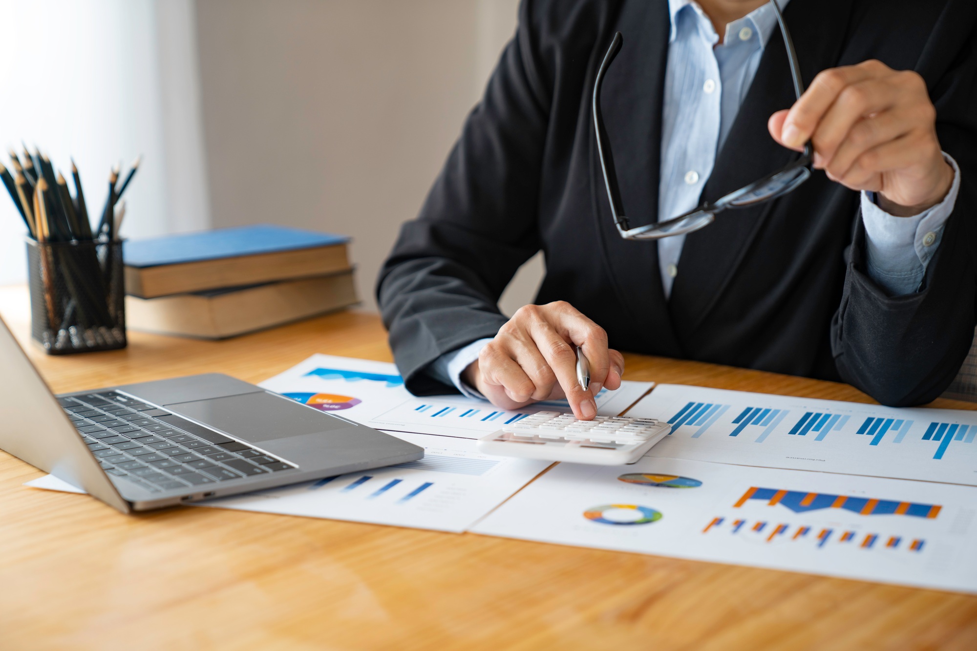 Asian businesswomen think with a calculator against data and statistics on graphs and charts. Analyz