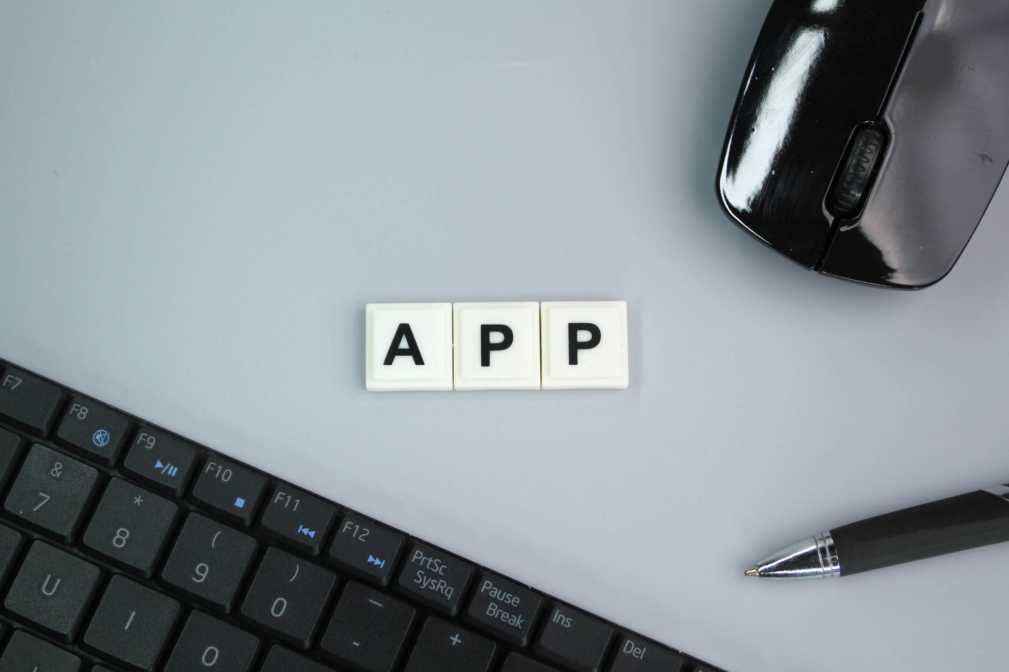 laptop keyboard, mouse and pen with the word App